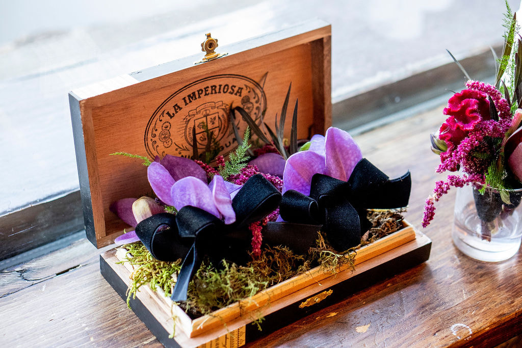 purple orchid boutonnieres in wooden box