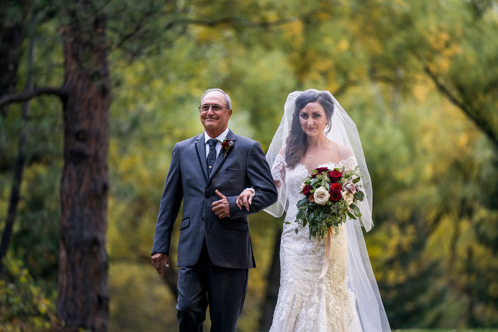 bride and dad walk down the aisle with blusher