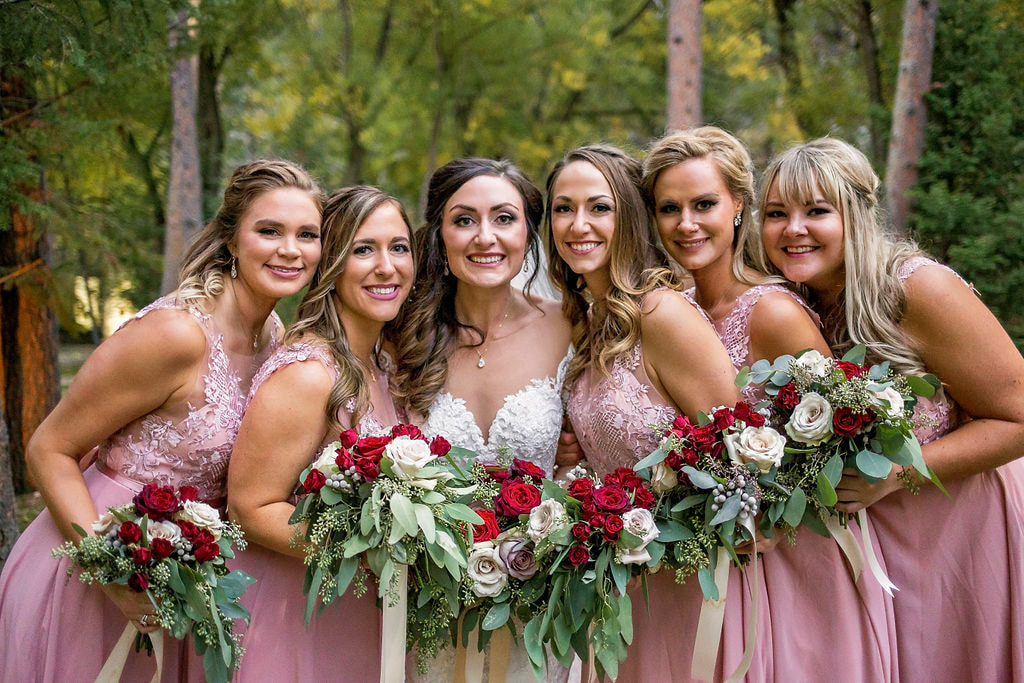 bride and bridesmaids in pink dresses with pink red white and green bouquets