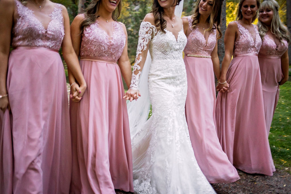 bride with bridesmaids in pink dresses walking hand in hand