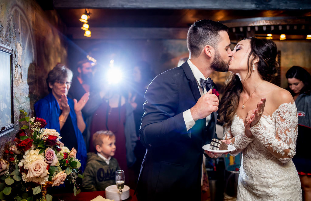 bride and groom kiss after feeding each other wedding cake