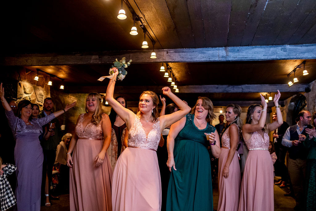 bridesmaid in pink dress catches toss bouquet