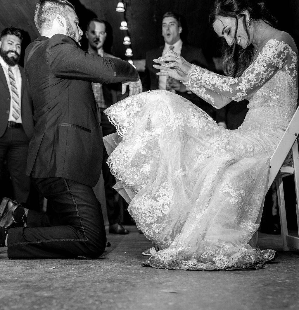 bride and groom laughing with men in the back durring garter removal