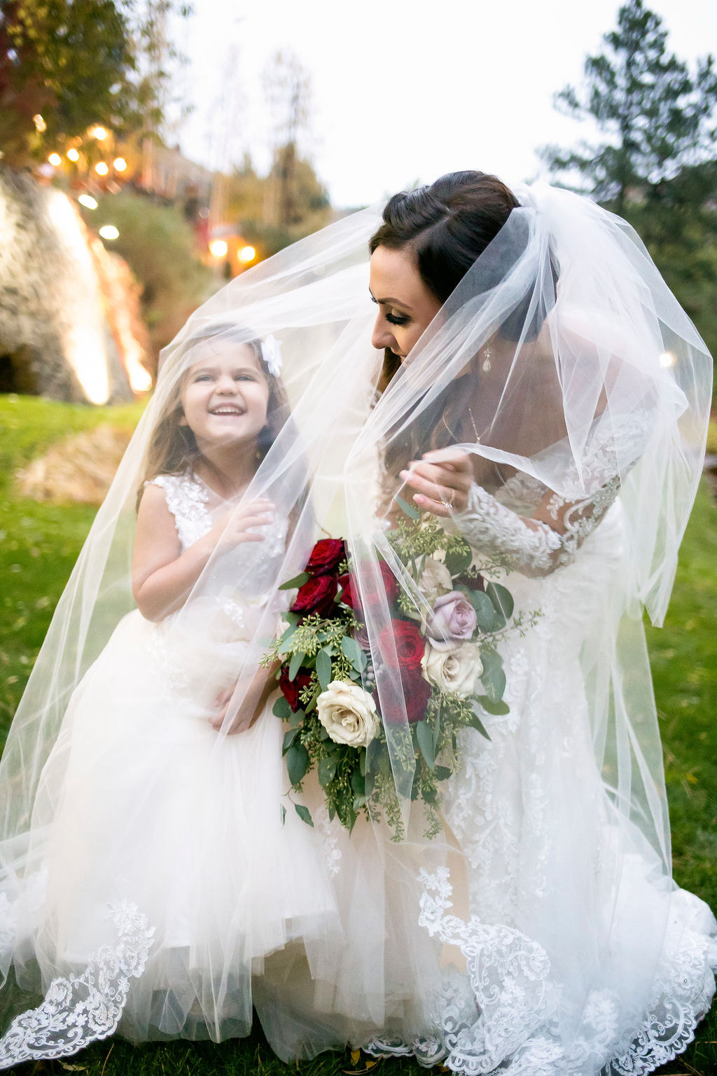 bride with flower girl under veil laughing