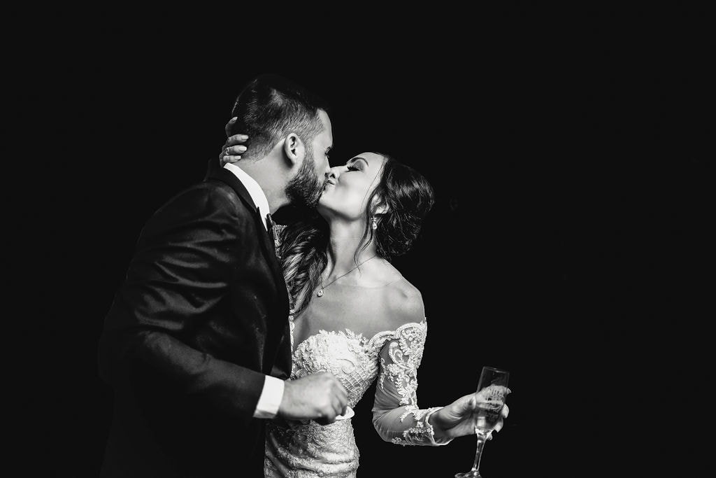 stunning black and white photo of bride and groom kissing with drink in hand at dunafon castle wedding